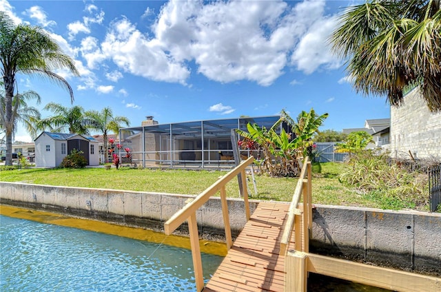 dock area with a lanai, a yard, a residential view, and a water view