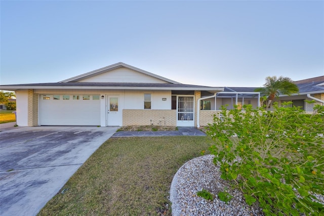 ranch-style home featuring driveway, brick siding, an attached garage, and a front yard