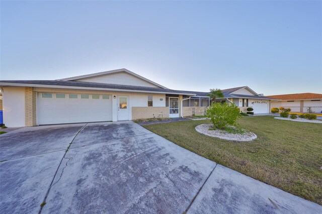 single story home with a front lawn, brick siding, a garage, and driveway