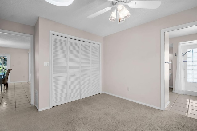 2462 Indian Trl E, Palm Harbor, FL 34683 - unfurnished bedroom with a closet, baseboards, tile patterned floors, carpet floors, and a textured ceiling