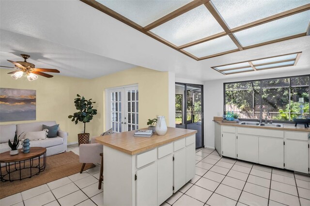 2462 Indian Trl E, Palm Harbor, FL 34683 - kitchen featuring french doors, light tile patterned floors, open floor plan, a sink, and white cabinets