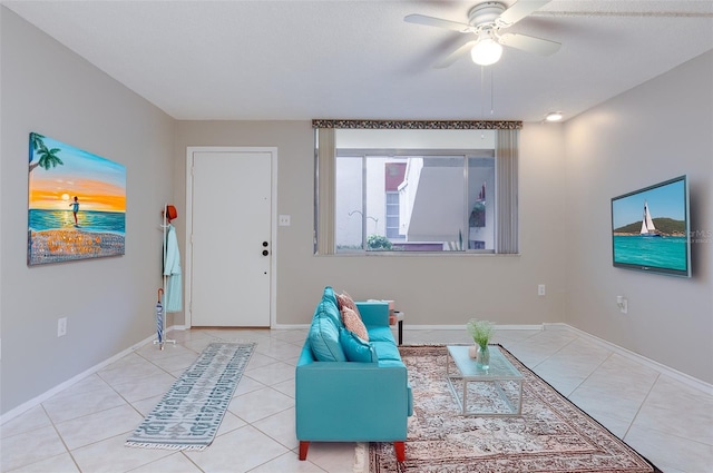 tiled living area with baseboards and a ceiling fan