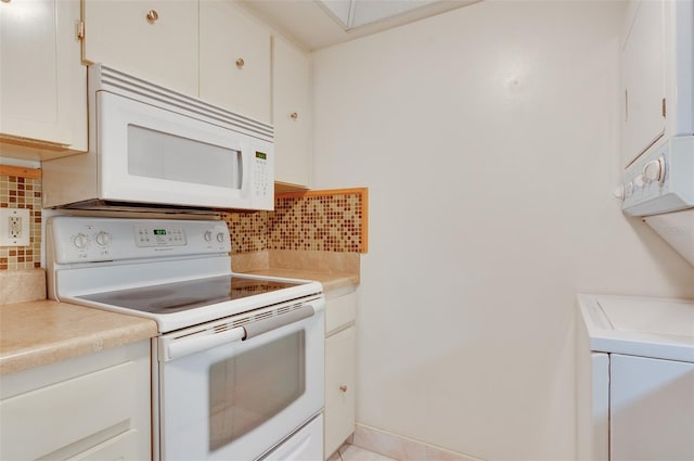 kitchen featuring white appliances, light countertops, stacked washer and clothes dryer, white cabinetry, and tasteful backsplash