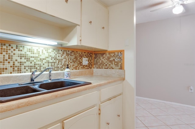 kitchen featuring light tile patterned floors, decorative backsplash, white cabinetry, and a sink