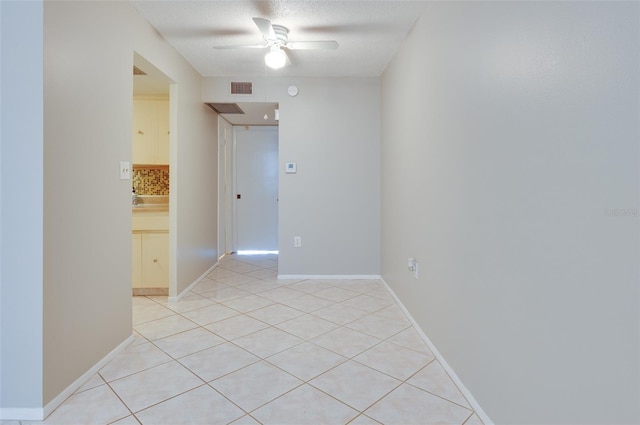 unfurnished room with light tile patterned floors, baseboards, visible vents, ceiling fan, and a textured ceiling