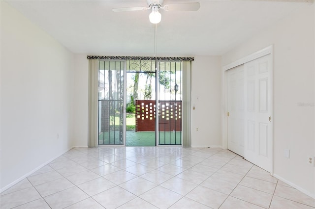 empty room featuring light tile patterned floors, a ceiling fan, and baseboards