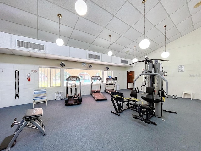 exercise room with vaulted ceiling, visible vents, and a drop ceiling