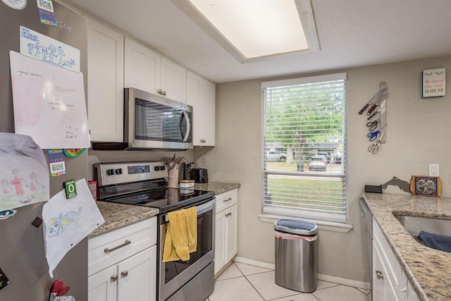 6475 23rd St N, Saint Petersburg, FL 33702 - kitchen with light tile patterned floors, light stone countertops, baseboards, white cabinets, and appliances with stainless steel finishes