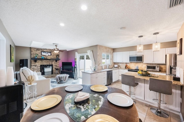 dining area with visible vents, a ceiling fan, light tile patterned flooring, a fireplace, and a toaster