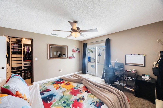 carpeted bedroom with visible vents, a walk in closet, baseboards, a textured ceiling, and access to outside