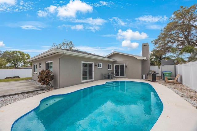 back of house with a fenced in pool, stucco siding, a chimney, a fenced backyard, and a patio area