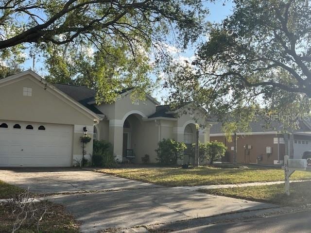 view of front of home with stucco siding, a front lawn, concrete driveway, and a garage