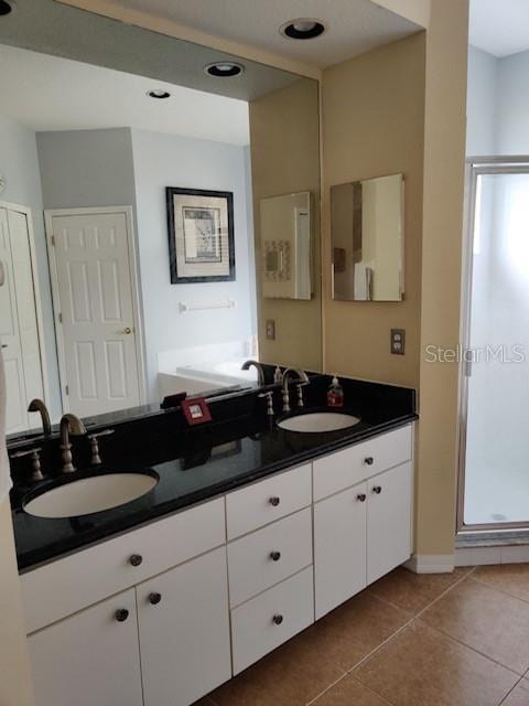 bathroom with tile patterned flooring, a shower stall, double vanity, and a sink