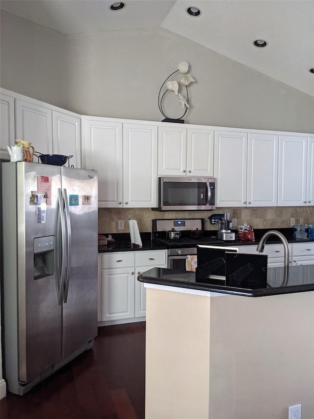 9636 Greenbank Dr, Riverview, FL 33569 - kitchen featuring lofted ceiling, white cabinets, dark countertops, and appliances with stainless steel finishes