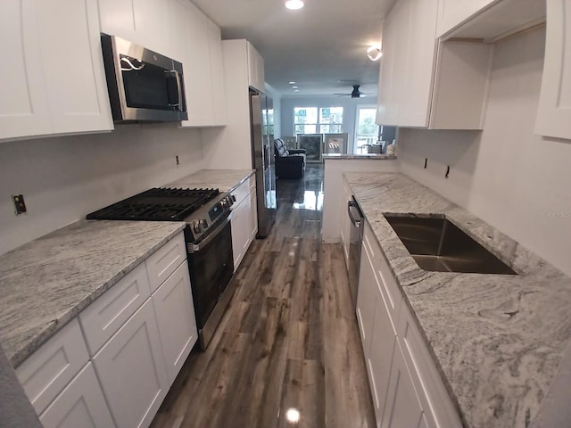 kitchen with dark wood-type flooring, white cabinetry, a sink, stainless steel appliances, and open floor plan