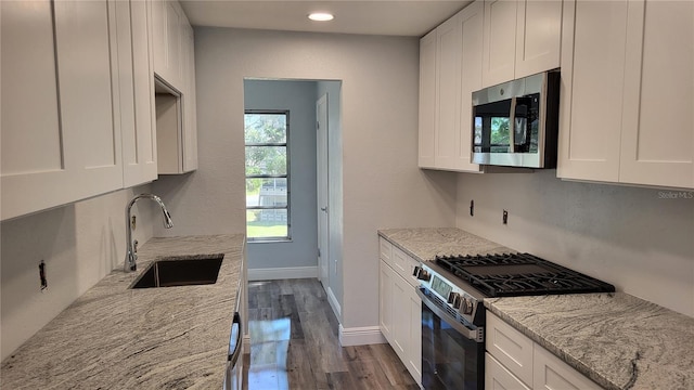 kitchen featuring appliances with stainless steel finishes, dark wood-style flooring, a sink, and white cabinetry