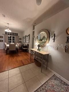 interior space featuring tile patterned flooring, baseboards, and an inviting chandelier