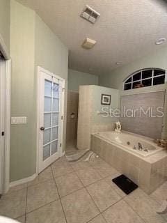 full bathroom with a bath, visible vents, tile patterned flooring, and a textured ceiling