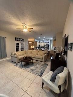 living area with a textured ceiling, ceiling fan, and tile patterned flooring