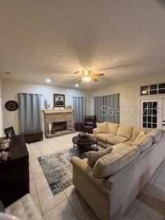 living area featuring a ceiling fan, recessed lighting, a fireplace with raised hearth, tile patterned flooring, and a textured ceiling