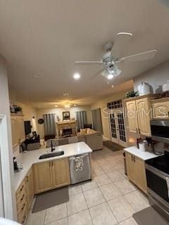 kitchen featuring a sink, a peninsula, appliances with stainless steel finishes, light countertops, and ceiling fan