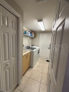 washroom featuring cabinet space, light tile patterned floors, separate washer and dryer, and visible vents