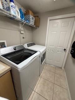 laundry room with light tile patterned floors, laundry area, baseboards, and separate washer and dryer