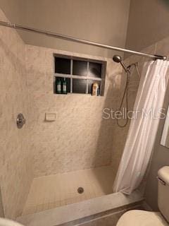 bathroom featuring tiled shower and toilet