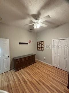 unfurnished bedroom with a ceiling fan, light wood-type flooring, a closet, and a textured ceiling