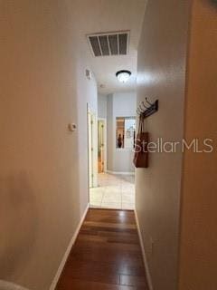 hallway featuring visible vents, baseboards, and wood finished floors