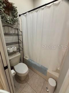 bathroom featuring tile patterned flooring, toilet, and shower / tub combo with curtain