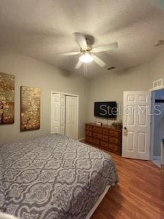 bedroom with visible vents, a ceiling fan, wood finished floors, a closet, and lofted ceiling