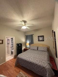 bedroom featuring ceiling fan, connected bathroom, a textured ceiling, and wood finished floors