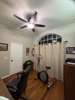 exercise room with a ceiling fan and wood finished floors