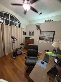 home office featuring a textured ceiling, wood finished floors, visible vents, and ceiling fan