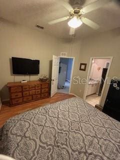 bedroom with visible vents, ensuite bath, a ceiling fan, and wood finished floors