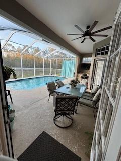 pool with glass enclosure, a patio, and a ceiling fan