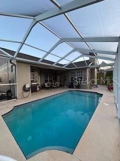 pool featuring glass enclosure and a patio area