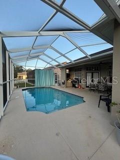 outdoor pool featuring glass enclosure and a patio area