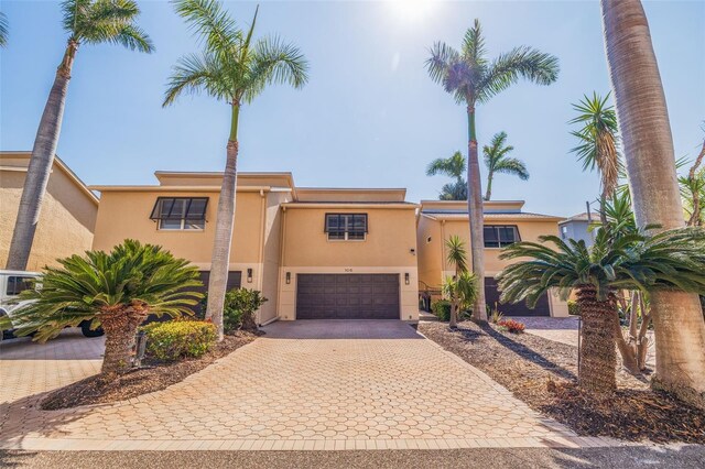 view of front of home featuring stucco siding, decorative driveway, and a garage