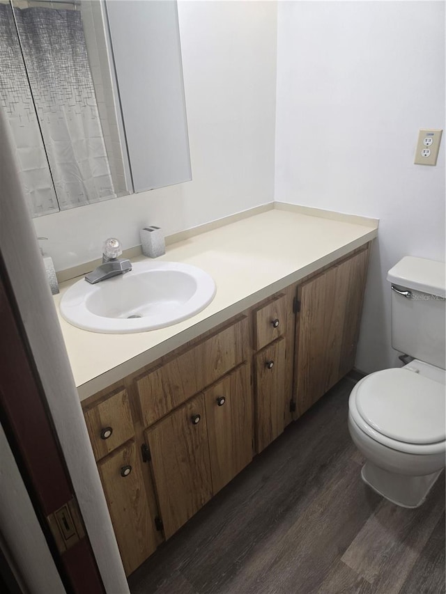 bathroom featuring a shower with shower curtain, toilet, wood finished floors, and vanity
