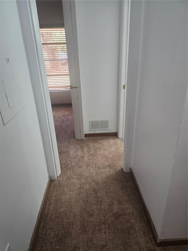 hall with carpet flooring, baseboards, and visible vents