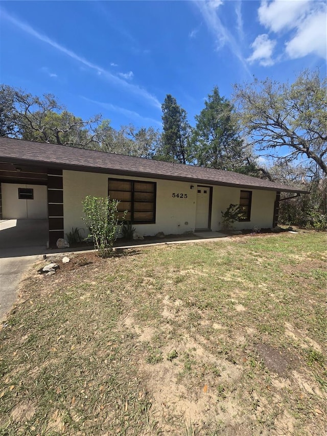 rear view of house with stucco siding, driveway, a yard, and an attached carport