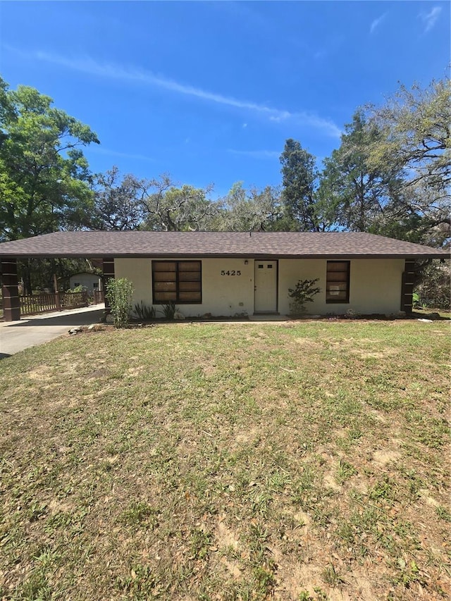 rear view of house featuring an attached carport, concrete driveway, and a lawn