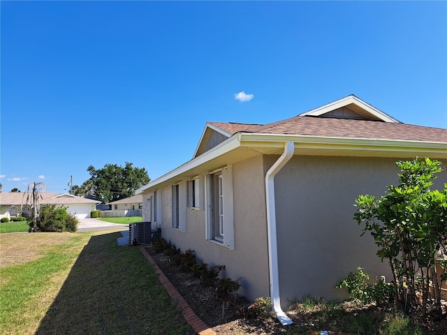 26 Clintwood Ave, Englewood, FL 34223 - view of side of home featuring stucco siding, a lawn, and a shingled roof