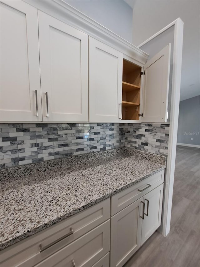26 Clintwood Ave, Englewood, FL 34223 - kitchen featuring open shelves, decorative backsplash, light stone countertops, wood finished floors, and white cabinetry
