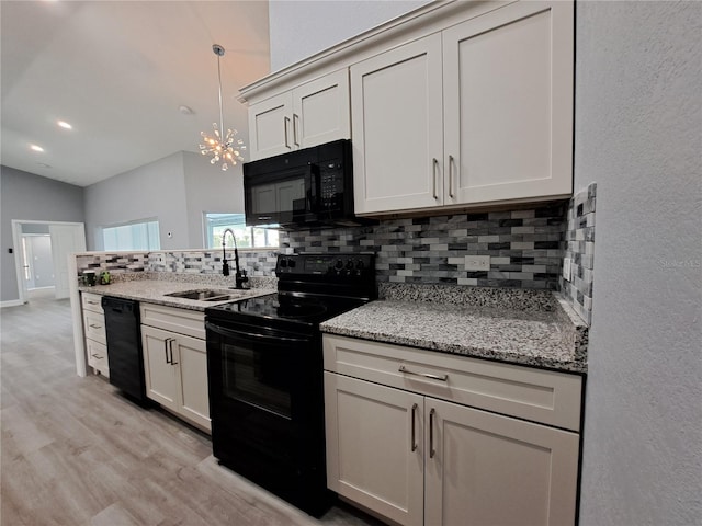 26 Clintwood Ave, Englewood, FL 34223 - kitchen with black appliances, backsplash, light wood-type flooring, a chandelier, and hanging light fixtures