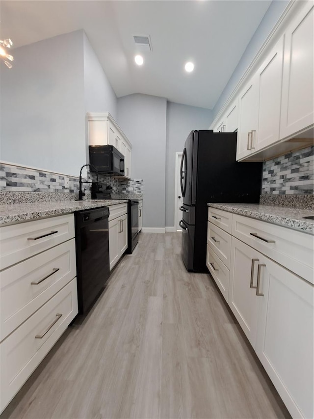 26 Clintwood Ave, Englewood, FL 34223 - kitchen featuring black appliances, decorative backsplash, white cabinets, light wood-style floors, and lofted ceiling