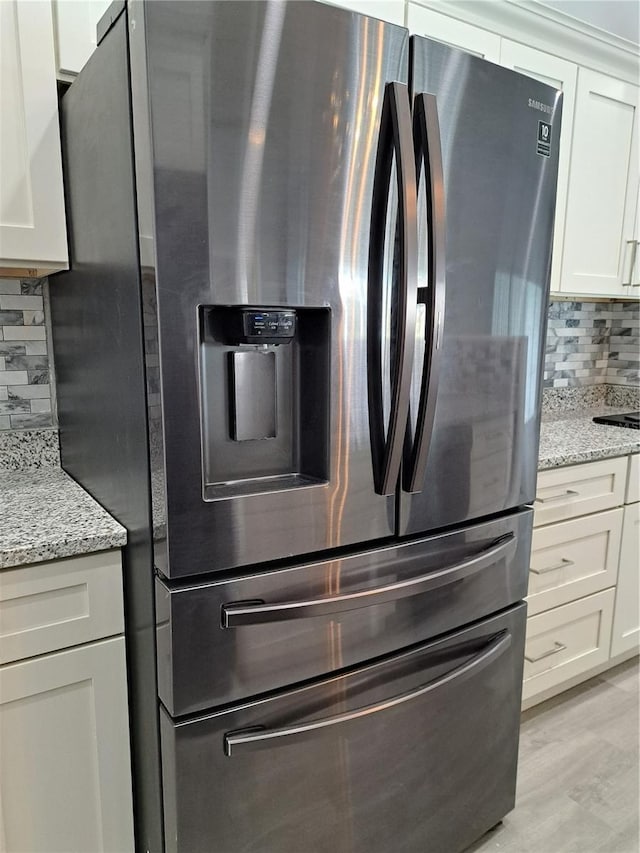 26 Clintwood Ave, Englewood, FL 34223 - kitchen featuring stainless steel fridge with ice dispenser, tasteful backsplash, white cabinets, and light stone counters