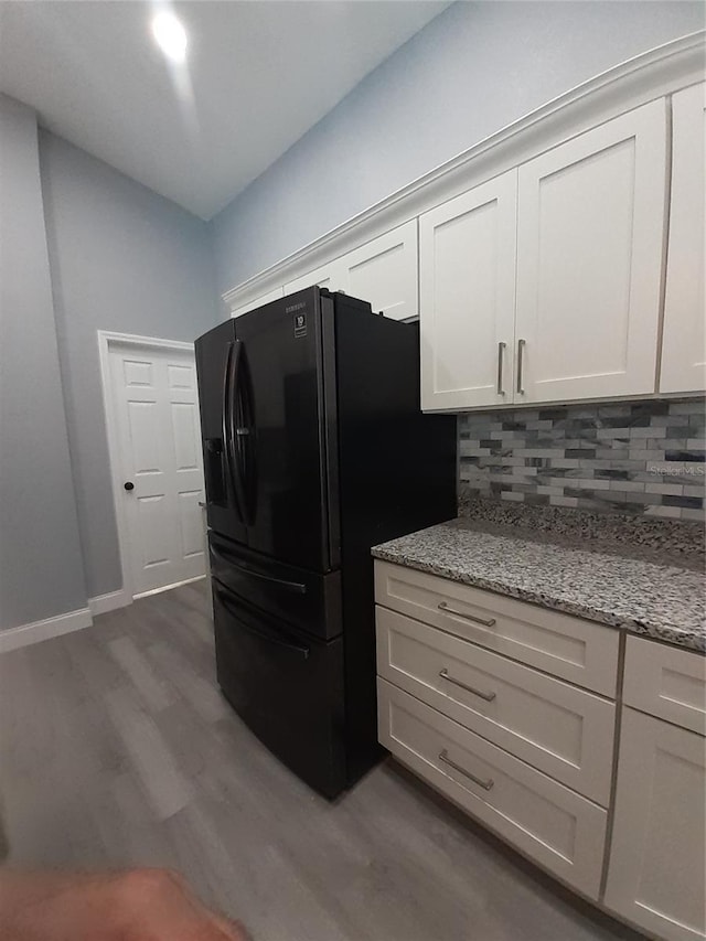 26 Clintwood Ave, Englewood, FL 34223 - kitchen with decorative backsplash, dark wood-style floors, black refrigerator with ice dispenser, and light stone countertops